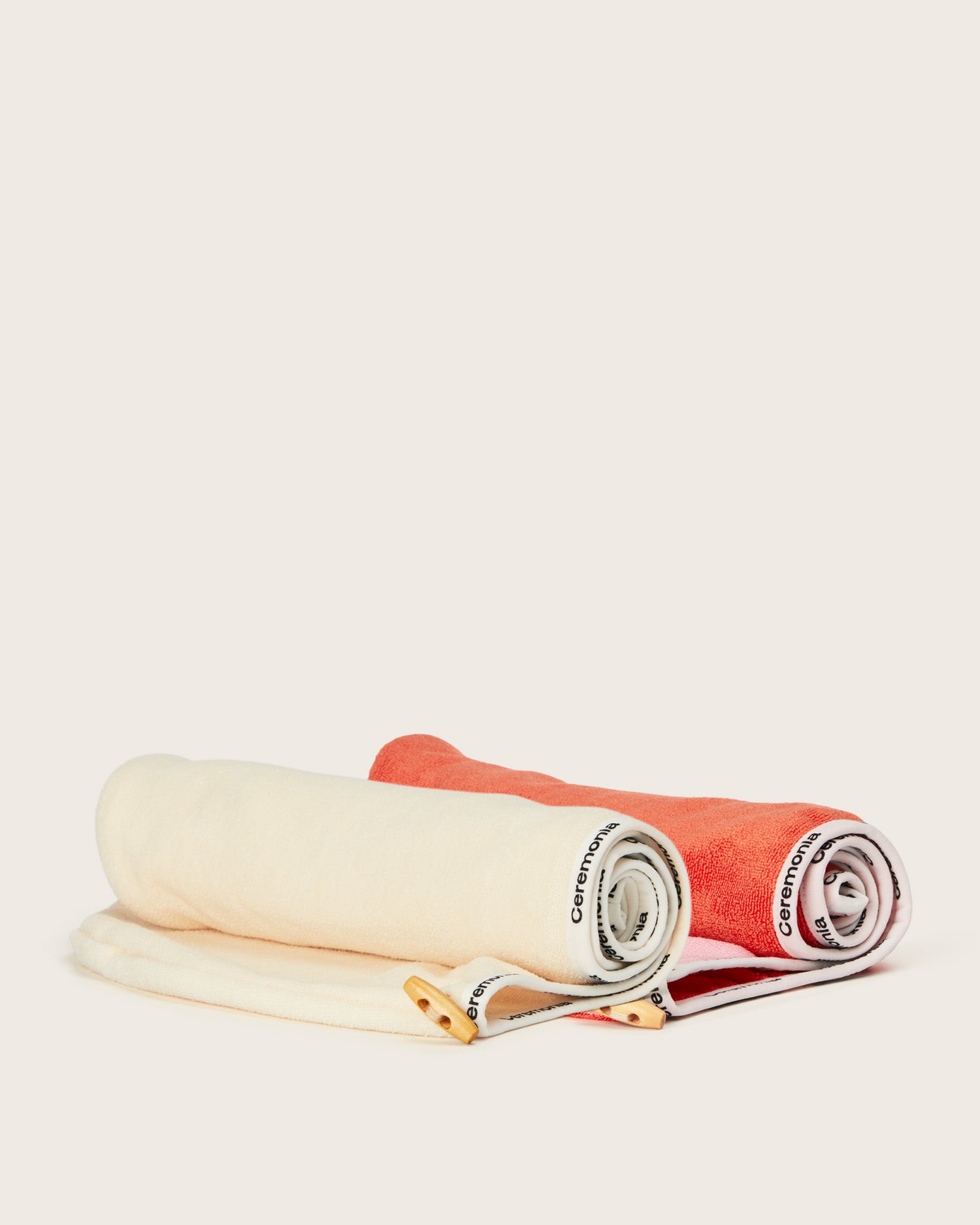 Hair towel set in cream and coral colors with Ceremonia tags, neatly rolled on a neutral background.