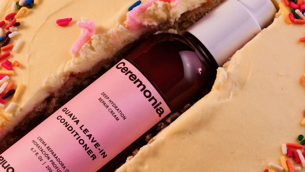 Ceremonia Guava Leave-In Conditioner nestled in frosted birthday cake with rainbow sprinkles.