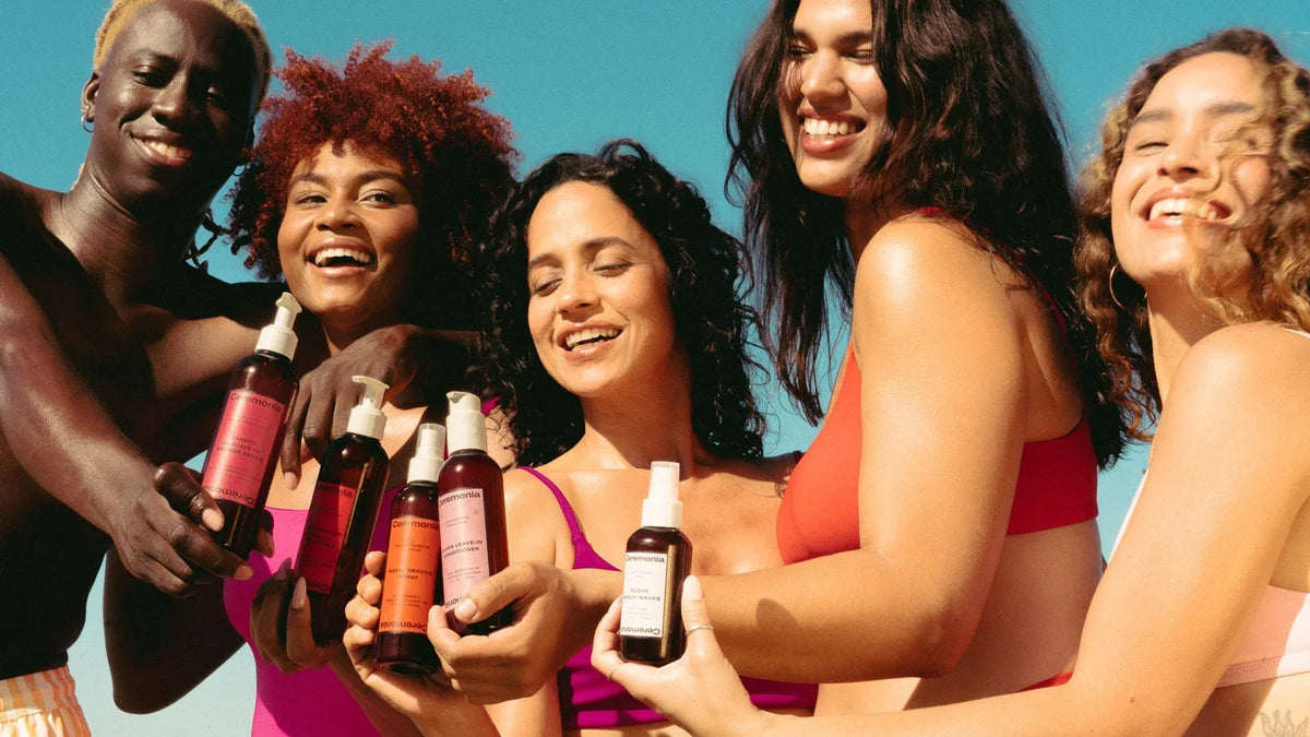 Five people with natural curly and wavy hair textures pose in colorful beachwear outdoors.