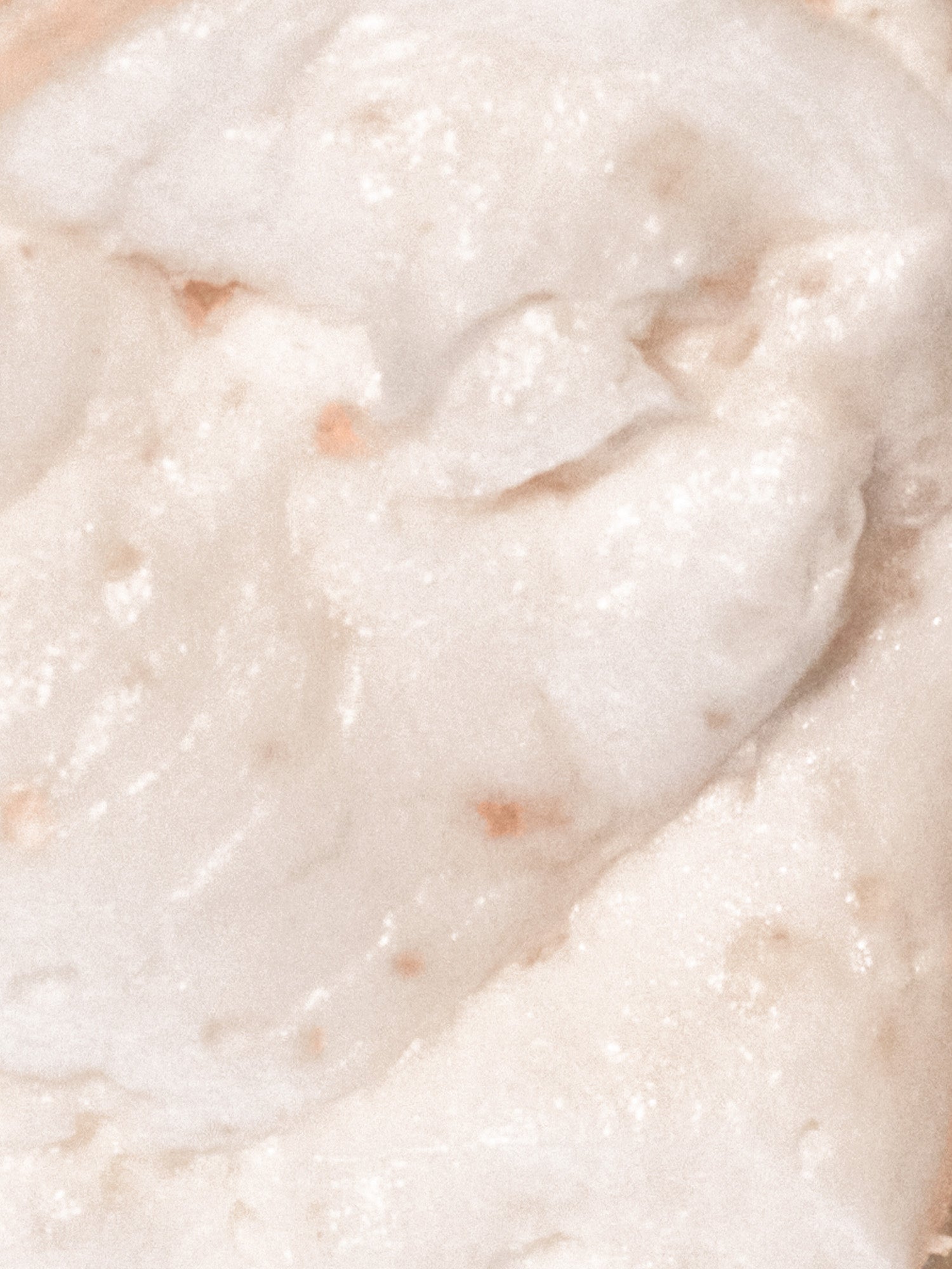 Creamy cream-colored hair scrub texture with fine exfoliating granules in macro close-up.
