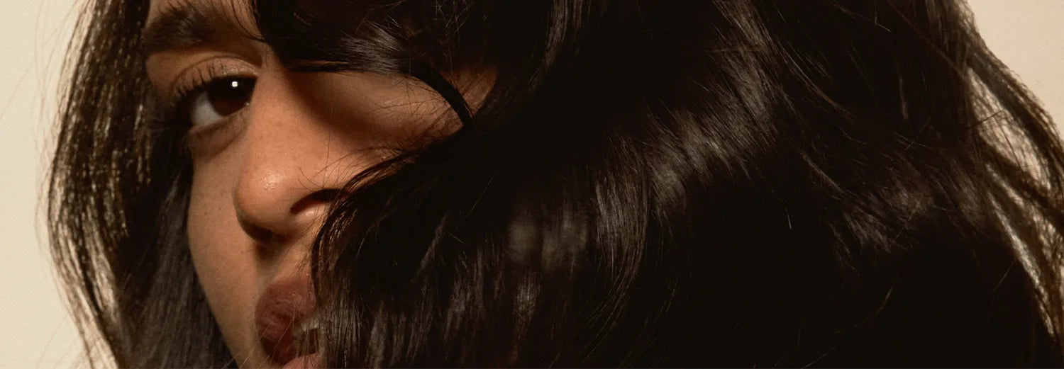 Close-up of smooth, shiny dark hair framing a face, showing frizz control results.