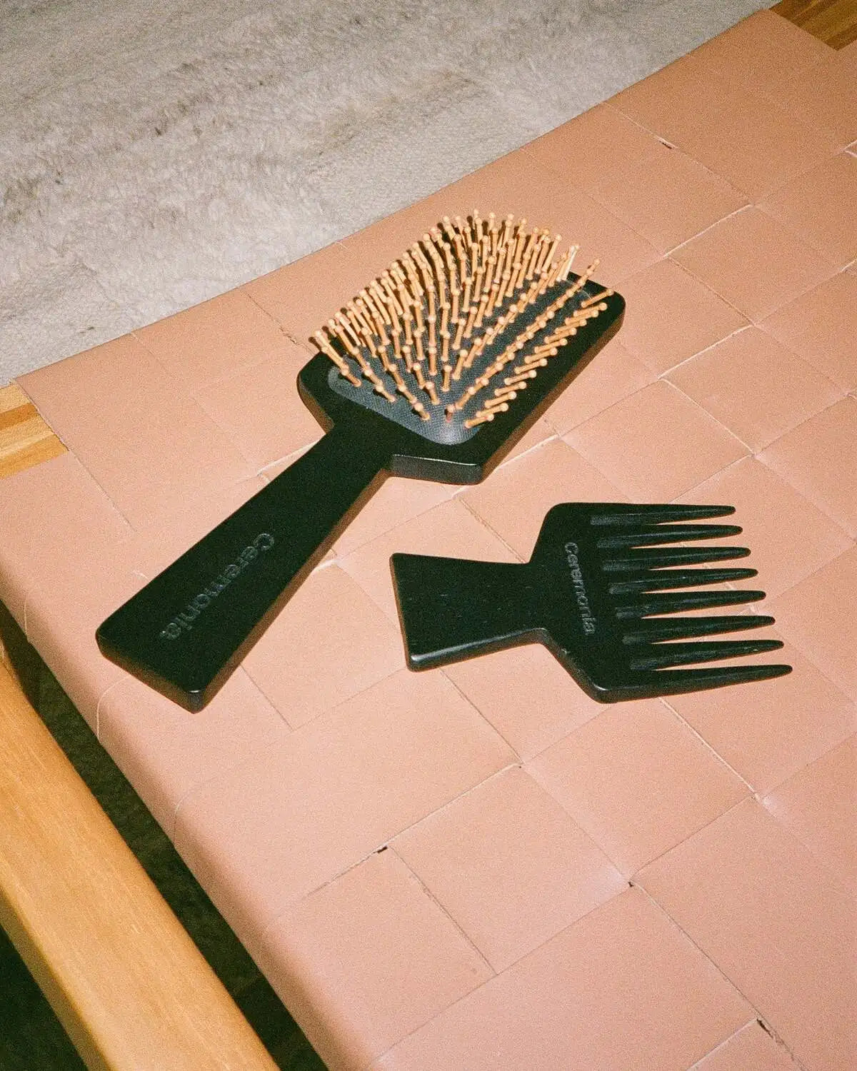 Hair brush and wide-tooth comb from Ceremonia placed on a woven pink chair.