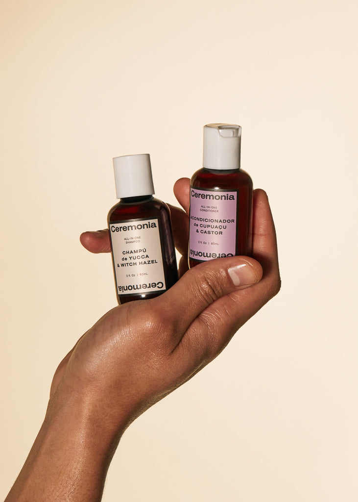 Weightless shampoo and conditioner minis held in hand against neutral background.