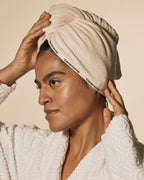 Beige hair towel wrapped around head with Ceremonia-branded trim and secure fit.