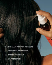 Guava hair detangler spray being applied to long dark hair for UV and heat protection.
