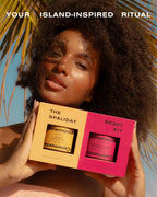 Papaya scalp scrub and guava hair mask kit held by woman with curly hair under palm trees.
