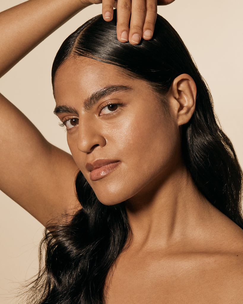 Hair styling gel creates a sleek, glossy finish on a woman’s smooth, center-parted hairstyle.