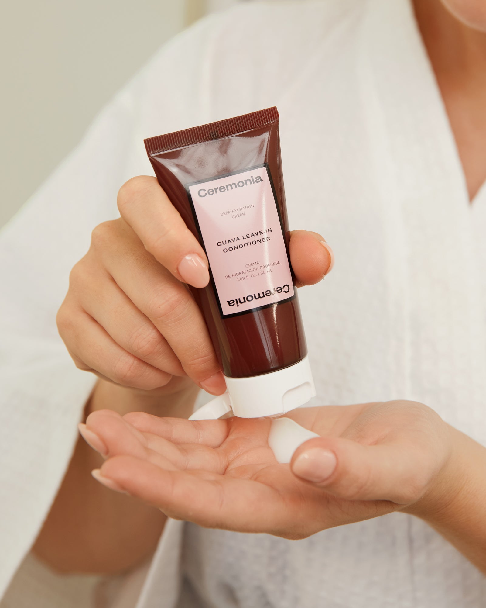 Leave-in conditioner from Ceremonia being dispensed into a hand, showing the creamy texture of the deep hydration formula.