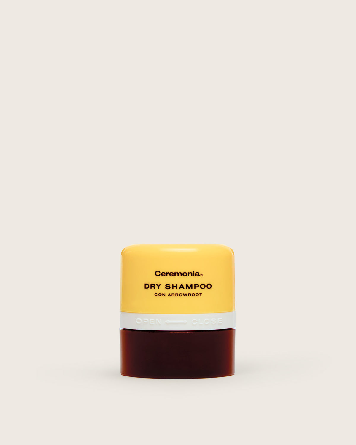 Non aerosol dry shampoo by Ceremonia in a yellow and brown container with twist-open applicator and arrowroot formula.