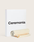 Hair towel rolled up beside Ceremonia gift box, featuring branded trim and wooden button.