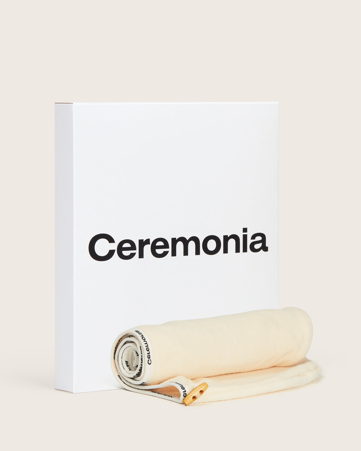 Hair towel rolled up beside Ceremonia gift box, featuring branded trim and wooden button.