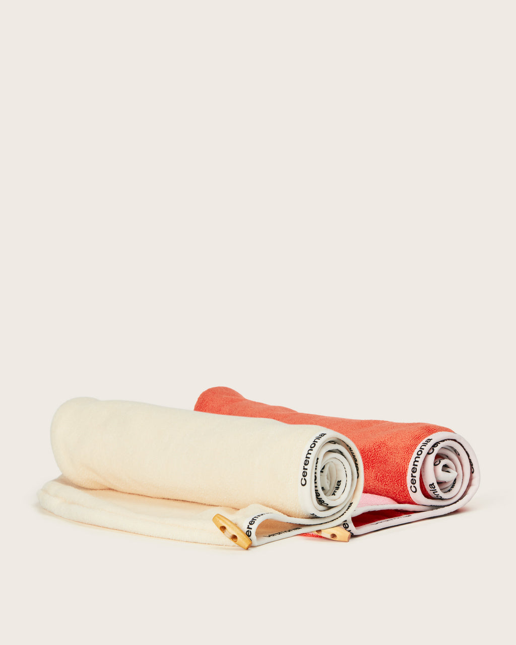 Hair towel set in cream and coral colors with Ceremonia tags, neatly rolled on a neutral background.
