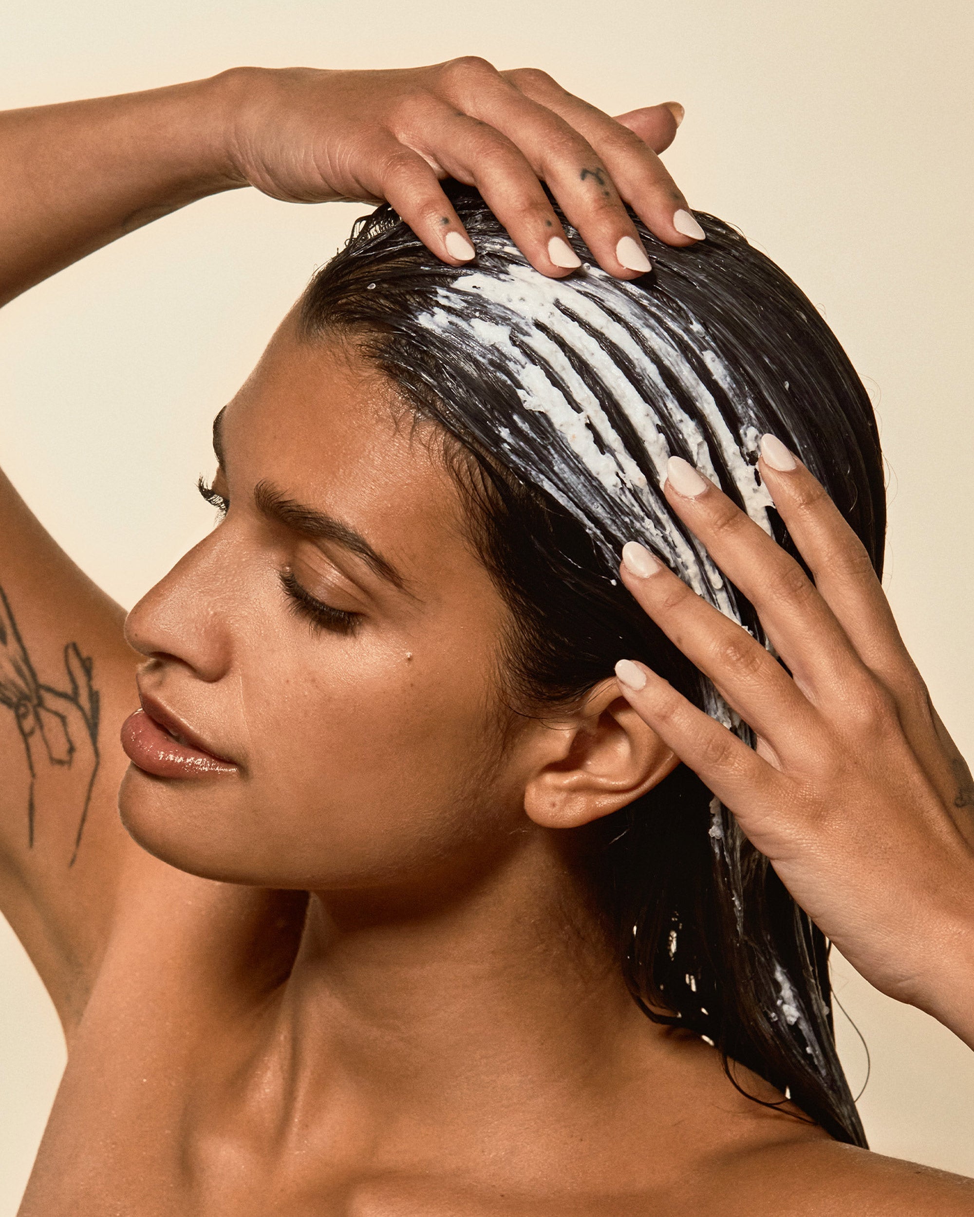 Hair mask being massaged into wet hair by a woman with manicured nails, promoting deep conditioning and repair.
