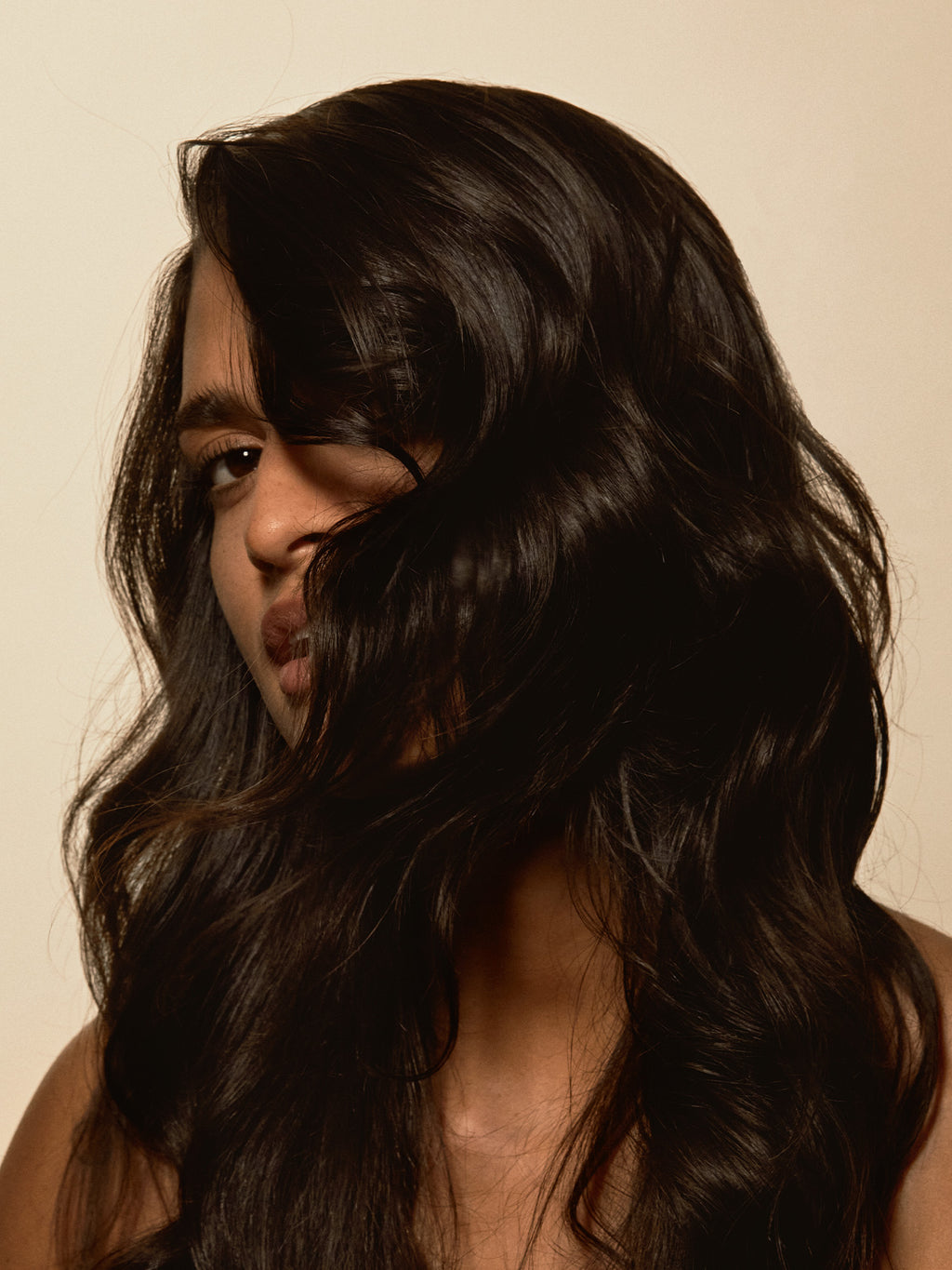 Exfoliating scalp mask results shown on a woman with smooth, shiny, voluminous hair cascading around her face.