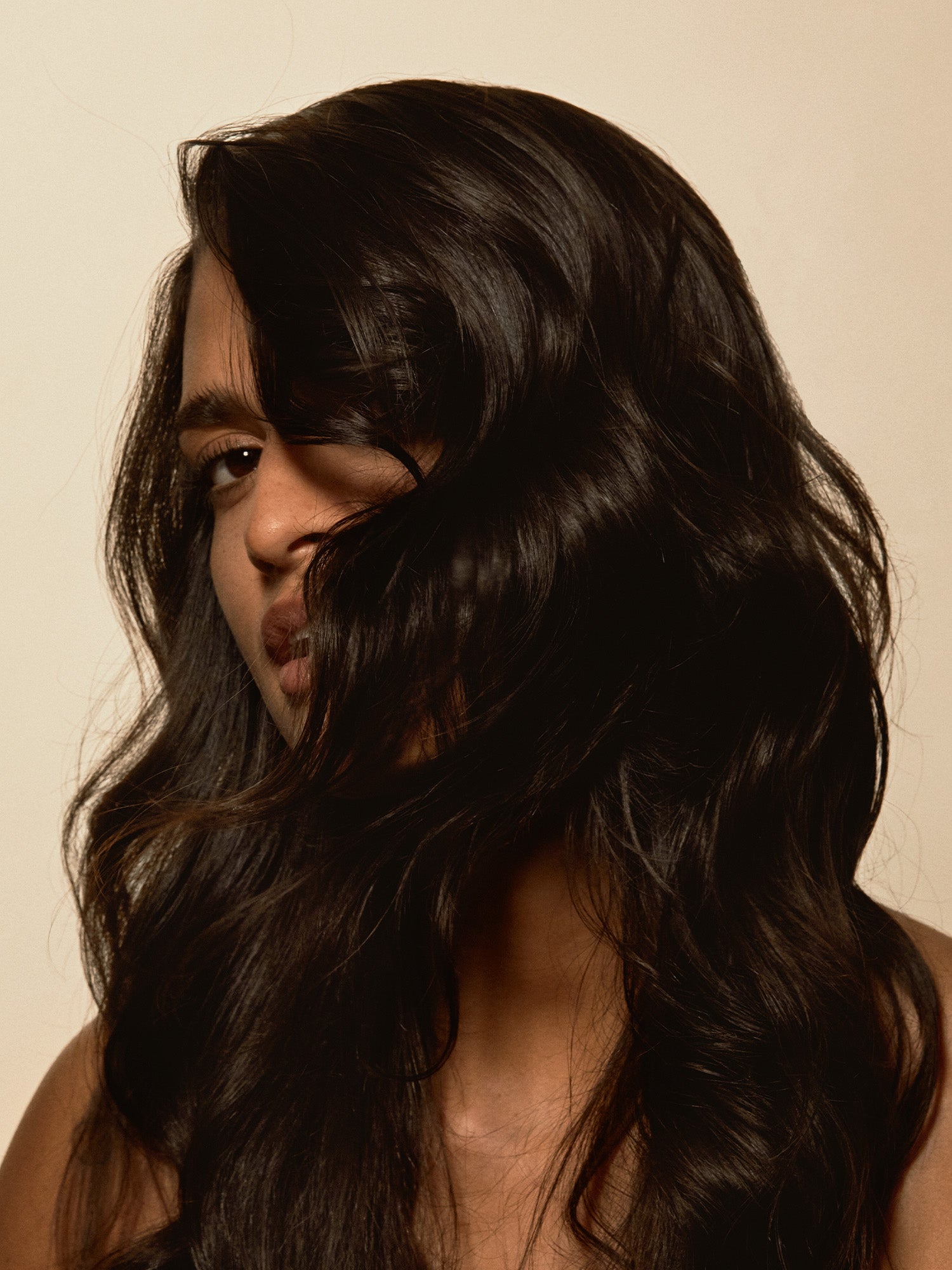 Exfoliating scalp mask results shown on a woman with smooth, shiny, voluminous hair cascading around her face.