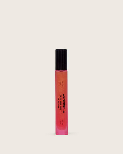 Perfume mist de Guava in a slim pink shimmer bottle with black cap, displayed on a light neutral background.