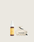 Scalp oil by Ceremonia shown with a white scalp massager, both designed for nourishing and stimulating the scalp.