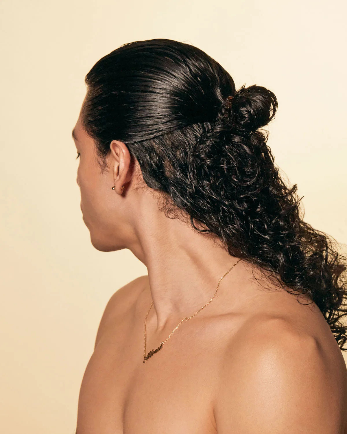 Back view of sleek slicked-back half-updo with defined curls styled using Pequi hair gel.