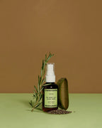 Ceremonia Oil Mist con Aloe Vera bottle beside fresh rosemary, aloe leaf, and chia seeds.