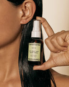 Ceremonia Oil Mist con Aloe Vera spray bottle held beside glossy dark hair.