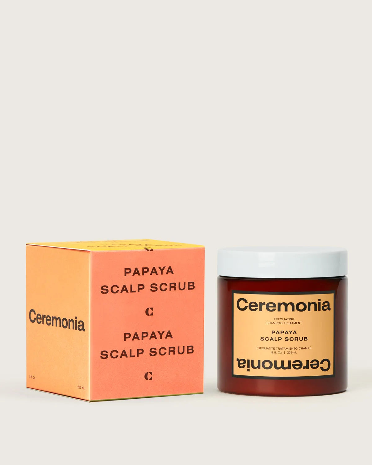Ceremonia Papaya Scalp Scrub amber jar beside its peach exfoliating shampoo treatment box.
