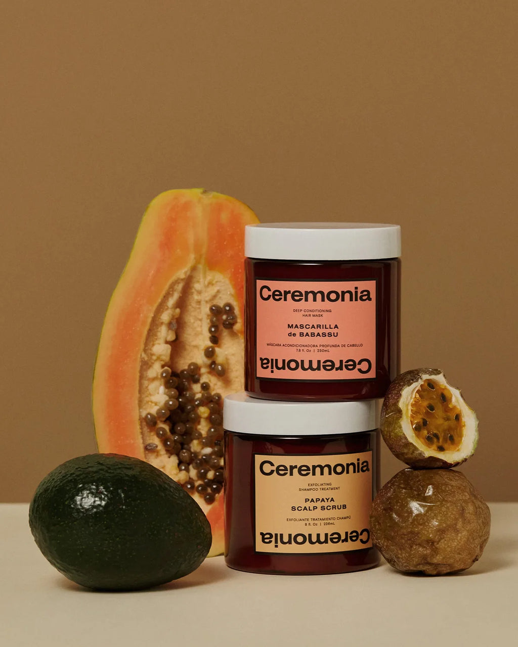Ceremonia Papaya Scalp Scrub and Mascarilla de Babassu jars stacked beside fresh papaya, avocado, and passionfruit.