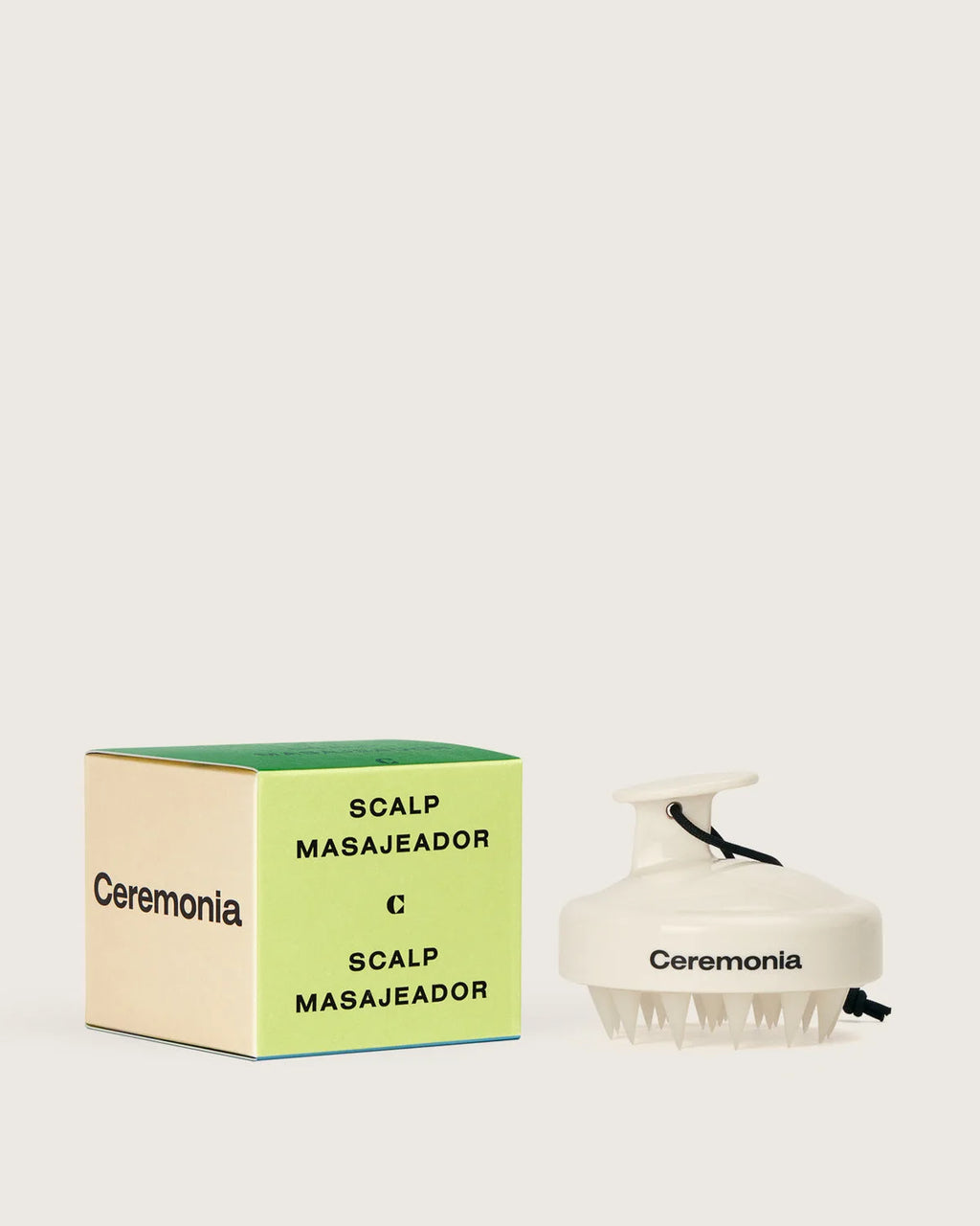 Ceremonia Scalp Masajeador handheld massager with silicone bristles beside its green branded box.