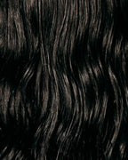 Close-up of glossy, frizz-free dark wavy hair showing shine after Oil Mist con Aloe Vera.