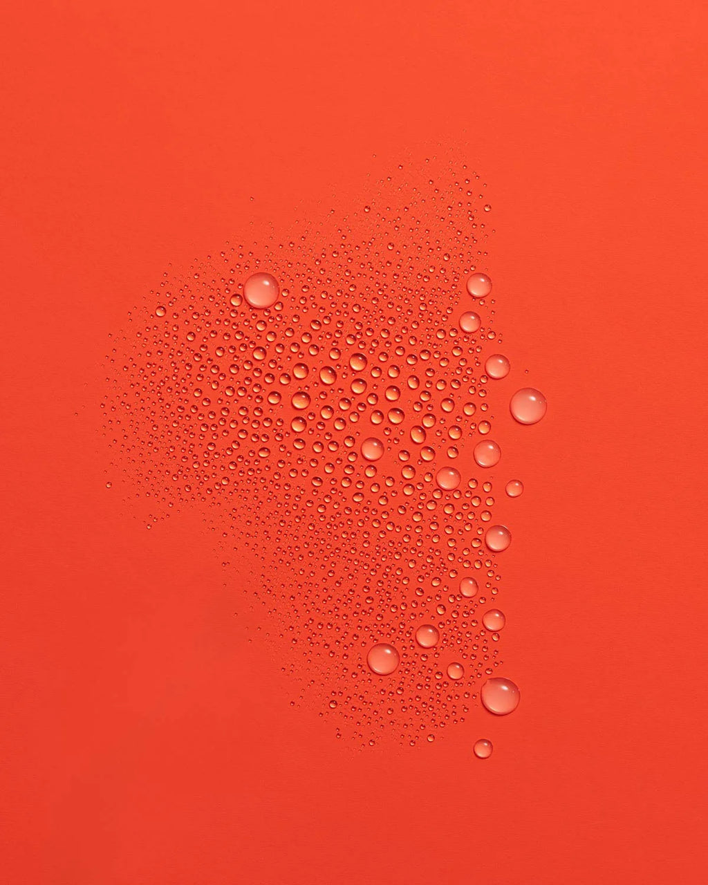 Fine mist of Guava Rescue Spray droplets scattered across a vivid red-orange surface.