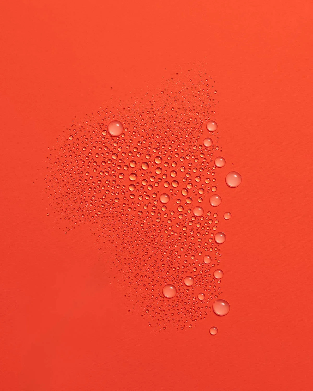 Fine mist of Guava Rescue Spray droplets scattered across a vivid red-orange surface.