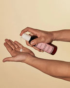 Guava leave-in conditioner being poured from an amber bottle into an open palm.