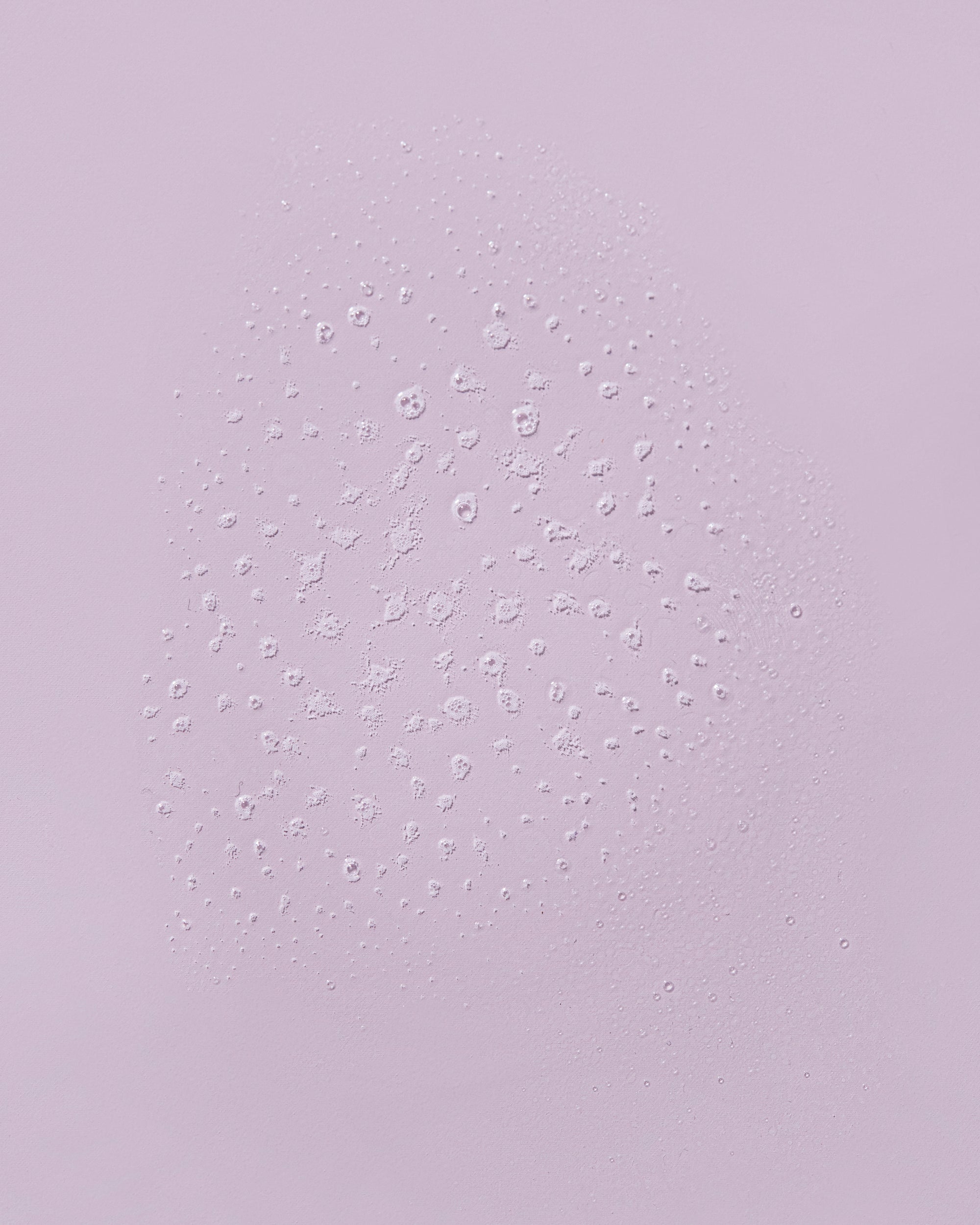 Misted spray droplets of Guava Beach Waves texturizing salt spray on a lavender surface.