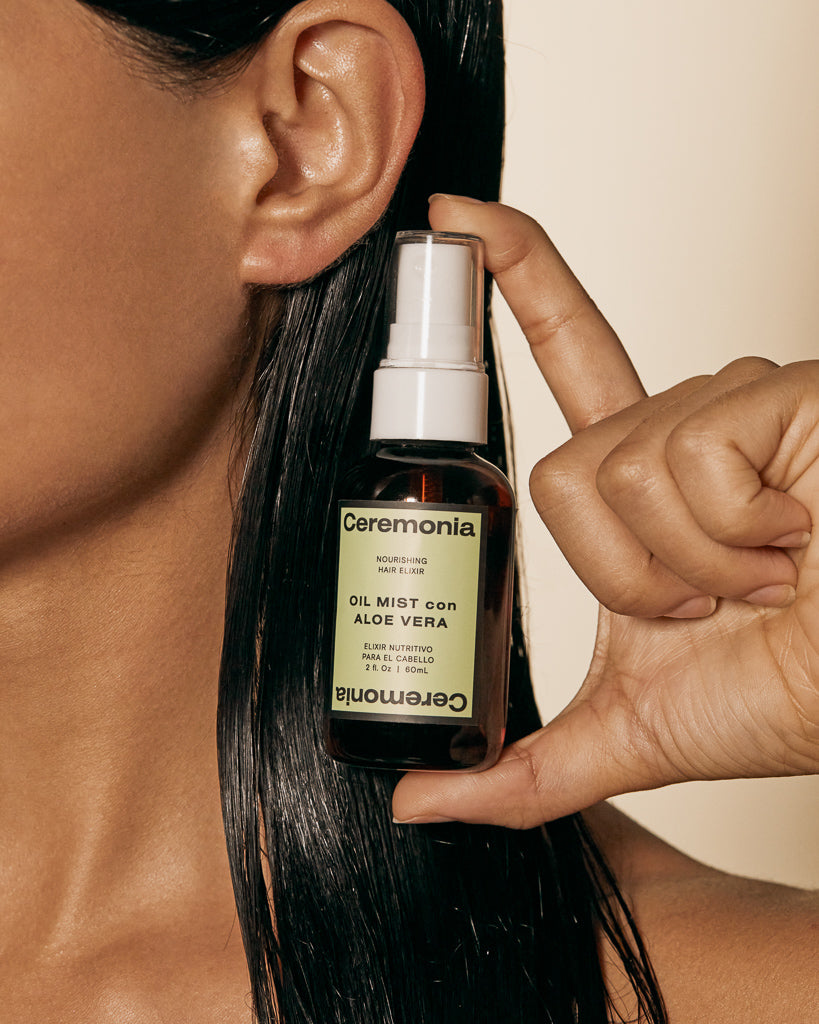 Ceremonia Oil Mist con Aloe Vera spray bottle held beside glossy dark hair.