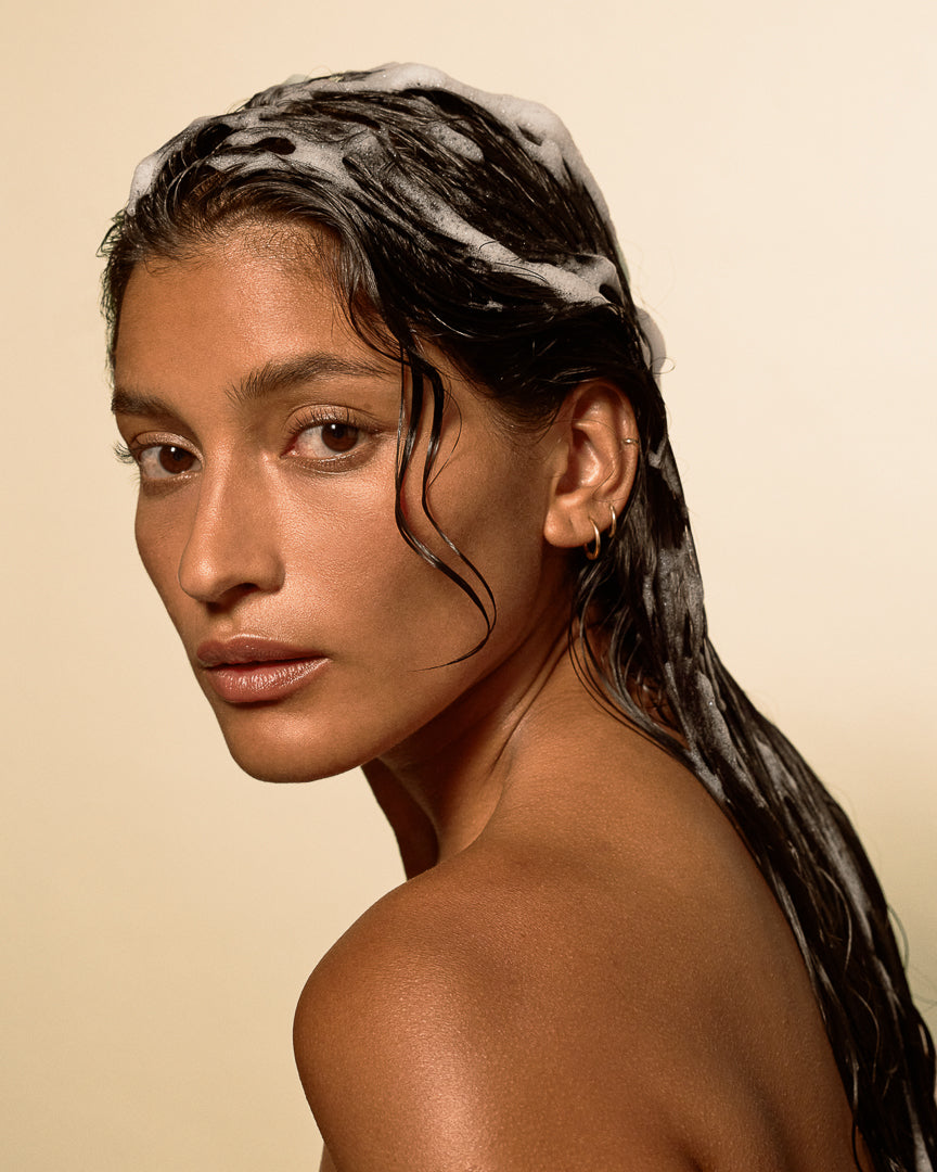 Person with wet, lathered hair showing Weightless Hydration shampoo foam on fine strands.